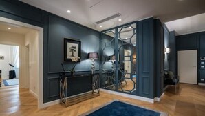 Un intérieur moderne avec des murs sombres, un plancher en bois, un tapis bleu, un tableau encadré et un bureau avec une lampe.