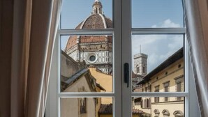 Une vue par la fenêtre sur un bâtiment doté d’un dôme et d’un clocher, ce qui laisse supposer qu’il s’agit d’un édifice historique ou religieux.