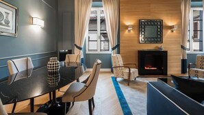 Un salon moderne avec une cheminée, un coin repas avec une table et des chaises, et une grande fenêtre avec des rideaux.