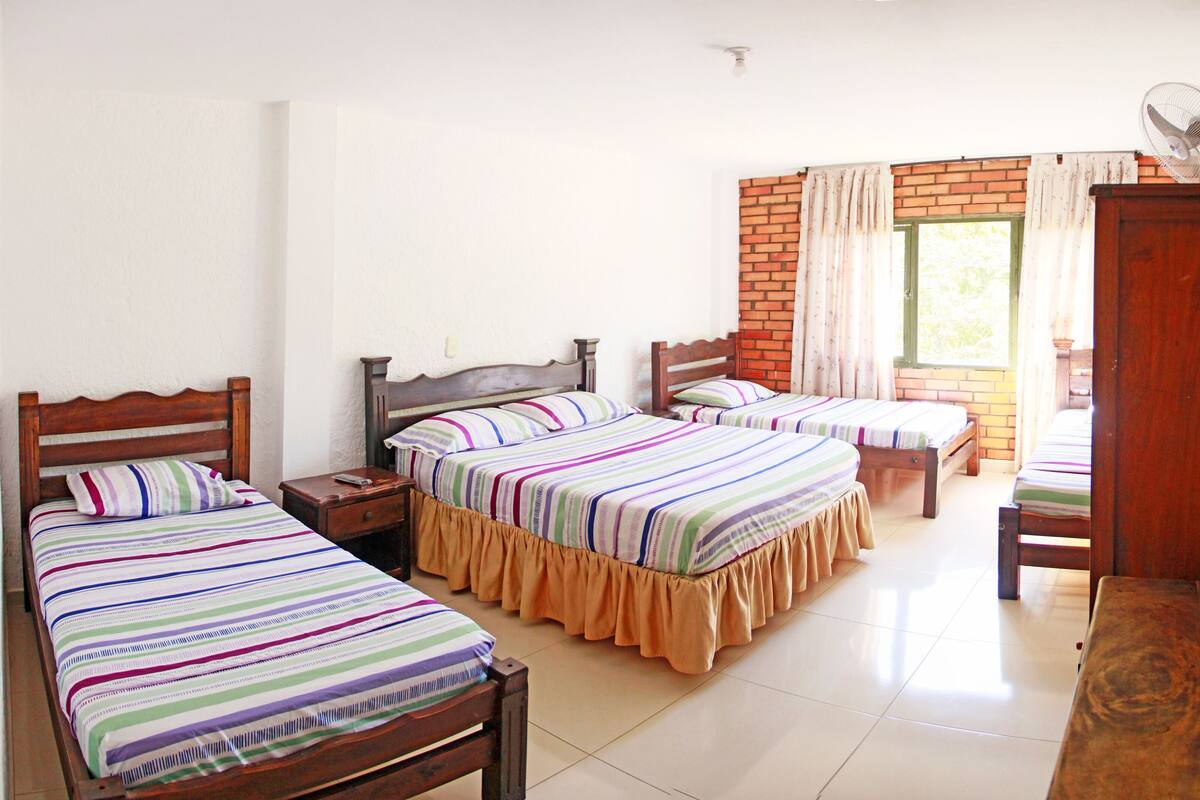 A room with two single beds, a wooden wardrobe, and a small table.