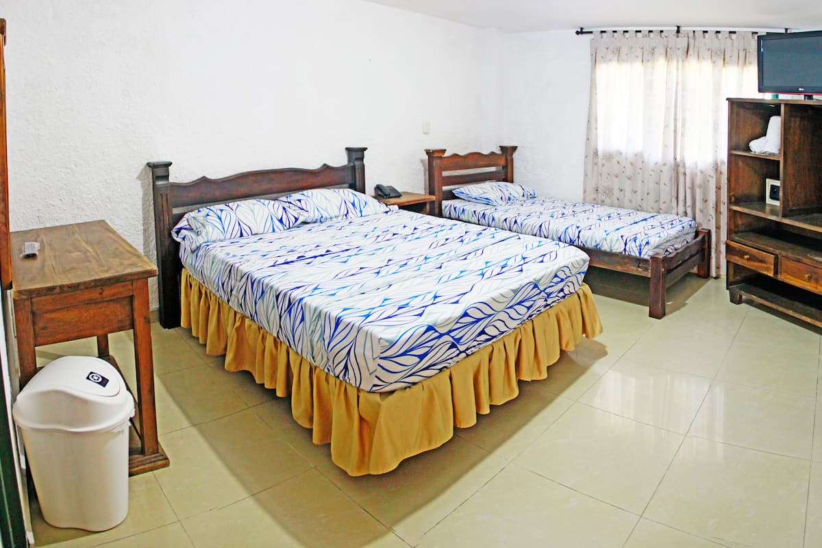 A hotel room with two beds, a wooden cabinet, a television, and a small table.