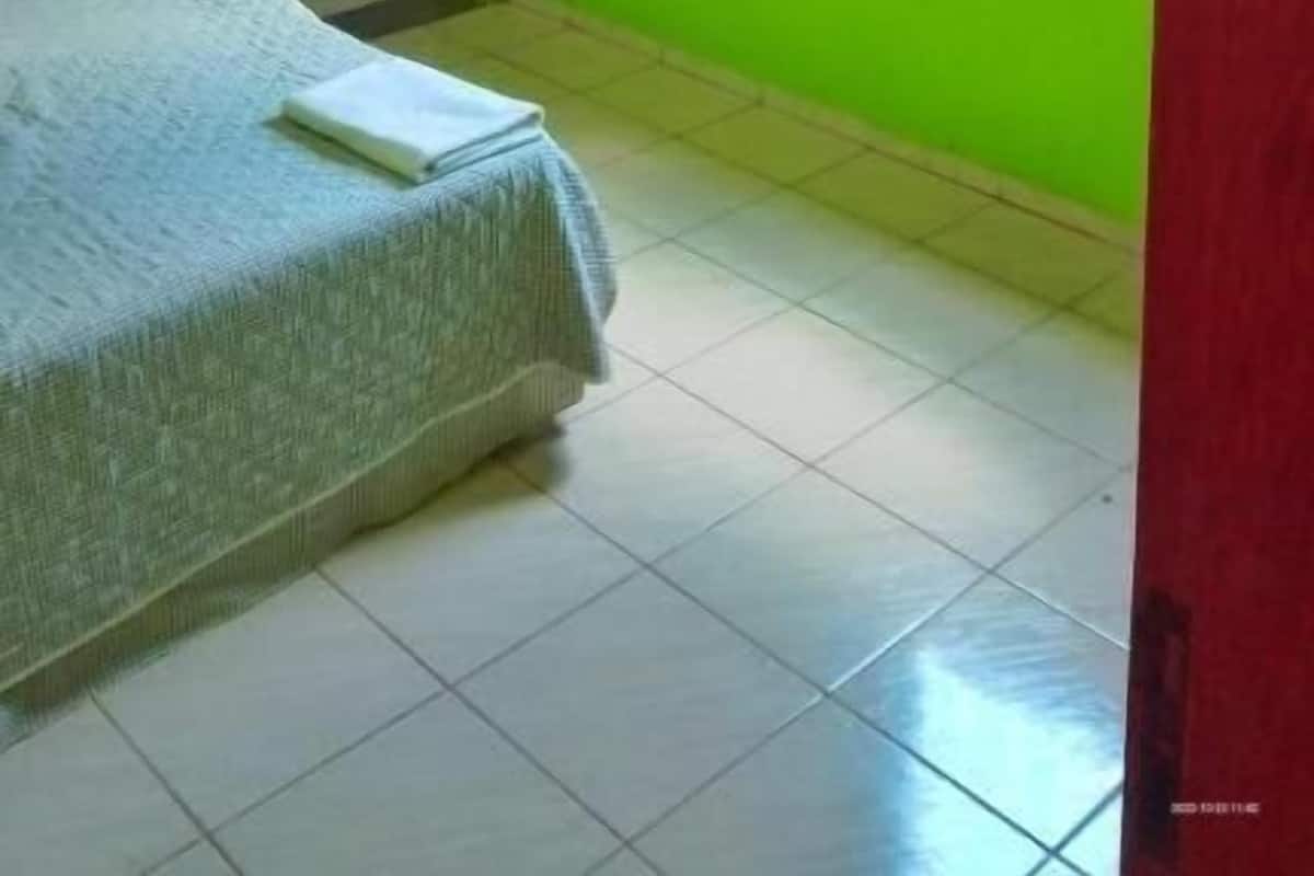 A room with bright green walls, a bed with a grey bedspread, a ceiling fan, and an air conditioning unit.
