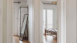 A hallway with a bed, a mirror, and a ceiling light fixture.