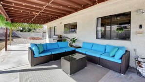 A covered outdoor seating area with a sectional sofa and a coffee table, a pergola with string lights, and a view of the backyard. - Spacious Home with Heated Pool! (Henderson)