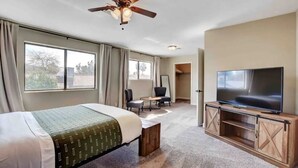 A hotel room with a bed, a TV, a desk, and a chair. - Spacious Home with Heated Pool! (Henderson)
