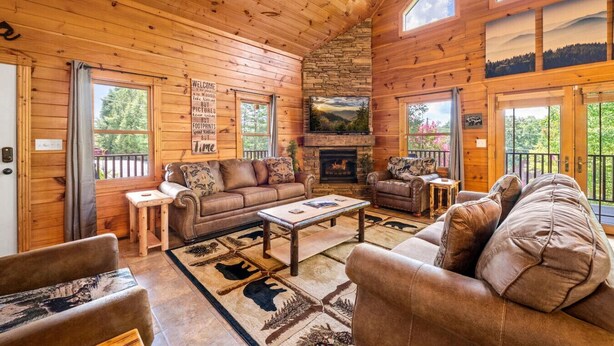 L’intérieur d’une cabane en rondins, avec une cheminée, des murs en bois et un coin salon confortable.