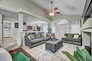 A spacious living area with a grey sofa set, a coffee table, and a ceiling fan.