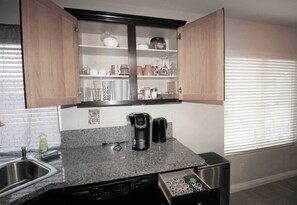 Cozinha compacta com bancada de granito, cafeteira, torradeira e gaveta lava-louças.