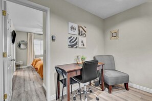 Quarto com escrivaninha, duas cadeiras, espelho e obras de arte na parede.