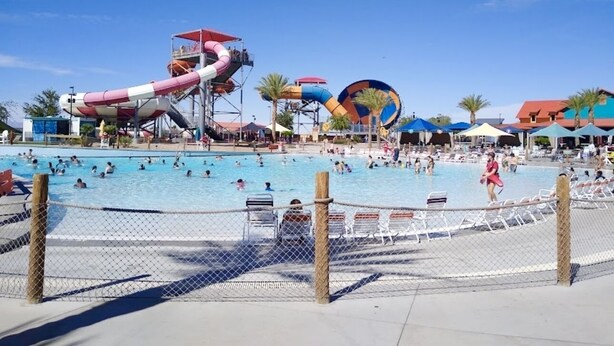 A water park with multiple slides and pools, surrounded by umbrellas and lounge chairs.