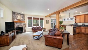 A spacious living room with a fireplace, leather sofas, a coffee table, and a TV. - Spacious 2-Story Home, walk to the beach, fenced yard, patio, bbq and fire pit (Pacific City)