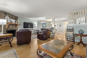 A spacious living room with a fireplace, leather sofas, a television, and a dining area.