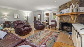 A cozy living room with leather sofas, a fireplace, and a stone wall. - Lakefront Townhome with Stunning Sunsets – StillWaters on Lake Martin (Dadeville)