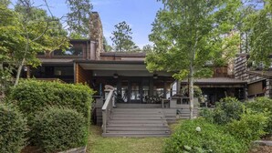 A modern house with a covered porch, a stone chimney, and a well-maintained garden. - Lakefront Townhome with Stunning Sunsets – StillWaters on Lake Martin (Dadeville)