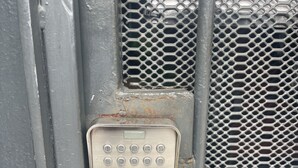 A metal keypad lock on a gray metal door with a mesh pattern. - Cozy Downtown Alajuela / 5min from Airport (Alajuela)