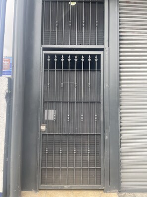 A black metal gate with a keypad lock, a mesh panel, and a roll-up shutter door. - Cozy Downtown Alajuela / 5min from Airport (Alajuela)