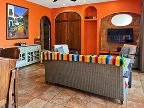 Una sala de estar con un sofá de mimbre, un televisor y un cuadro en la pared.
