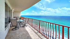 Un balcon avec vue sur l’océan, une table avec des chaises et une rambarde rouge.