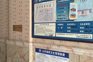 A bulletin board with various notices and documents, including a blue sign with text and a smaller blue sign below it. - Shangrao Hualong Hotel (Shangrao)