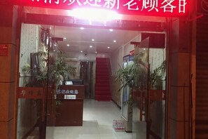 Ingresso di un hotel con reception, una scala e piante in vaso.