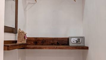 A corner room with a wooden shelf, a small safe, and a mirror.