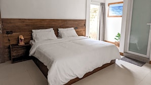 A bedroom with a wooden headboard, a bed with white bedding, a ceiling fan, and a view of the outdoors through a glass door. - Dhoadhi Retreat (Thulusdhoo Island)