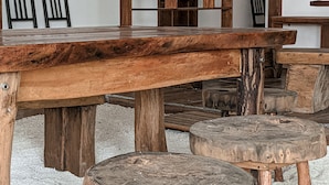 A rustic wooden dining table with stools, a wooden partition, and a simple chair arrangement. - Dhoadhi Retreat (Thulusdhoo Island)