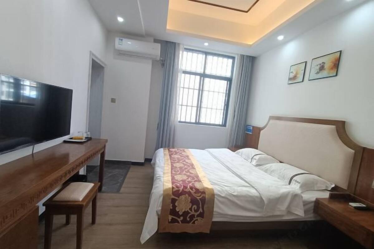 A hotel room with a bed, a desk, a television, and a window with curtains.