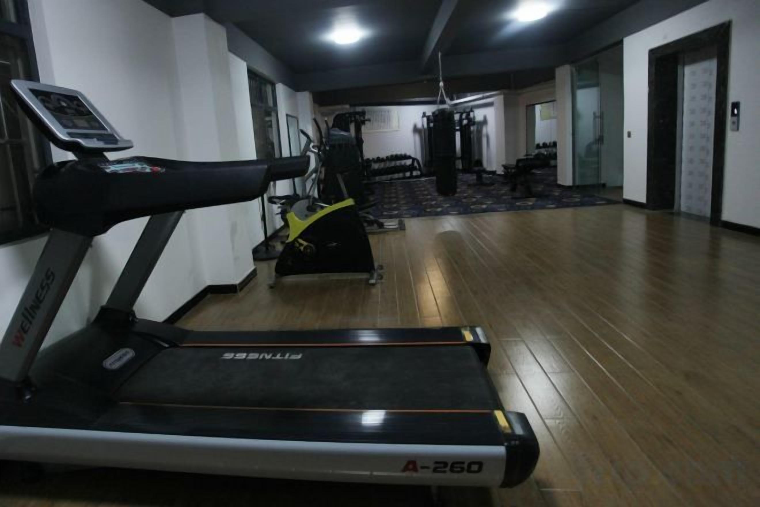 Un gimnasio con cintas de correr, bicicletas estáticas y máquinas de pesas.