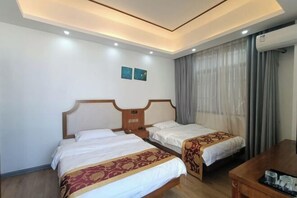 Quarto de hotel com duas camas, cabeceira de madeira, uma mesa com bandeja e um aparelho de ar condicionado.