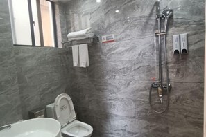 Uma casa de banho moderna com sanita, lavatório e chuveiro.