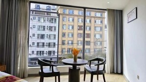 Una habitación de hotel con un ventanal grande, una mesa redonda con dos sillas y una cama.