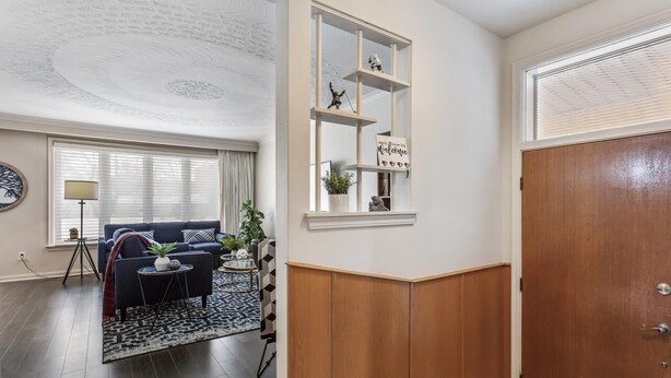 A living room with a dark blue sofa, a small round table, and a patterned rug. There is a bookshelf with decorative items and a sign on the wall. - Cosy Spacious 3+2 bedroom house , one bus to subway station (Toronto)