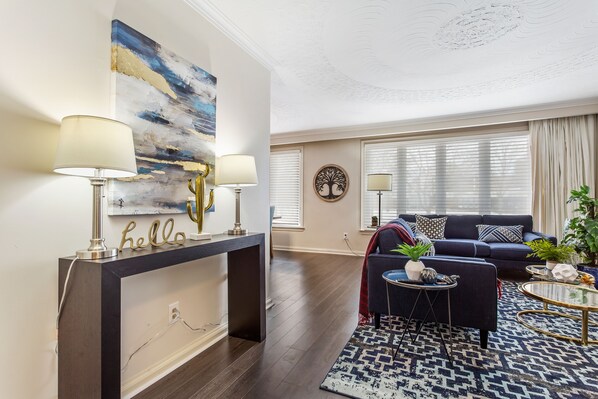 A modern living room with a dark wood floor, a blue sofa, a coffee table, and a console table with lamps.
