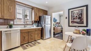 A modern kitchen with wooden cabinets, stainless steel appliances, and a dining area with a table and chairs. - Cosy Spacious 3+2 bedroom house , one bus to subway station (Toronto)
