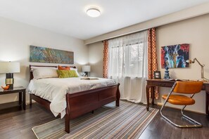 A neatly arranged bedroom with a bed, bedside tables, a desk, and a chair.