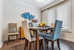 A dining area with a wooden table, four chairs, and a decorative blue wall piece.