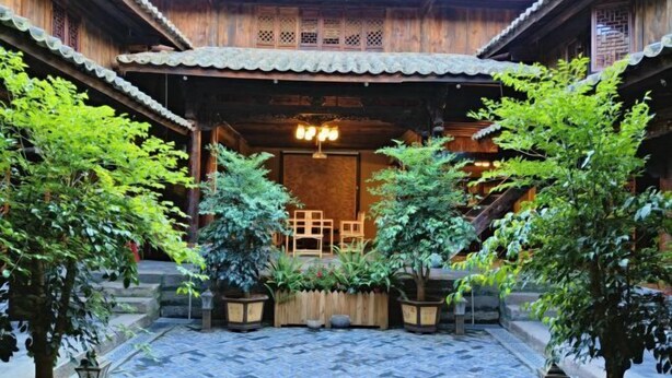 En traditionell byggnad i trä med en innergård med plattor, krukväxter och ett trästaket.