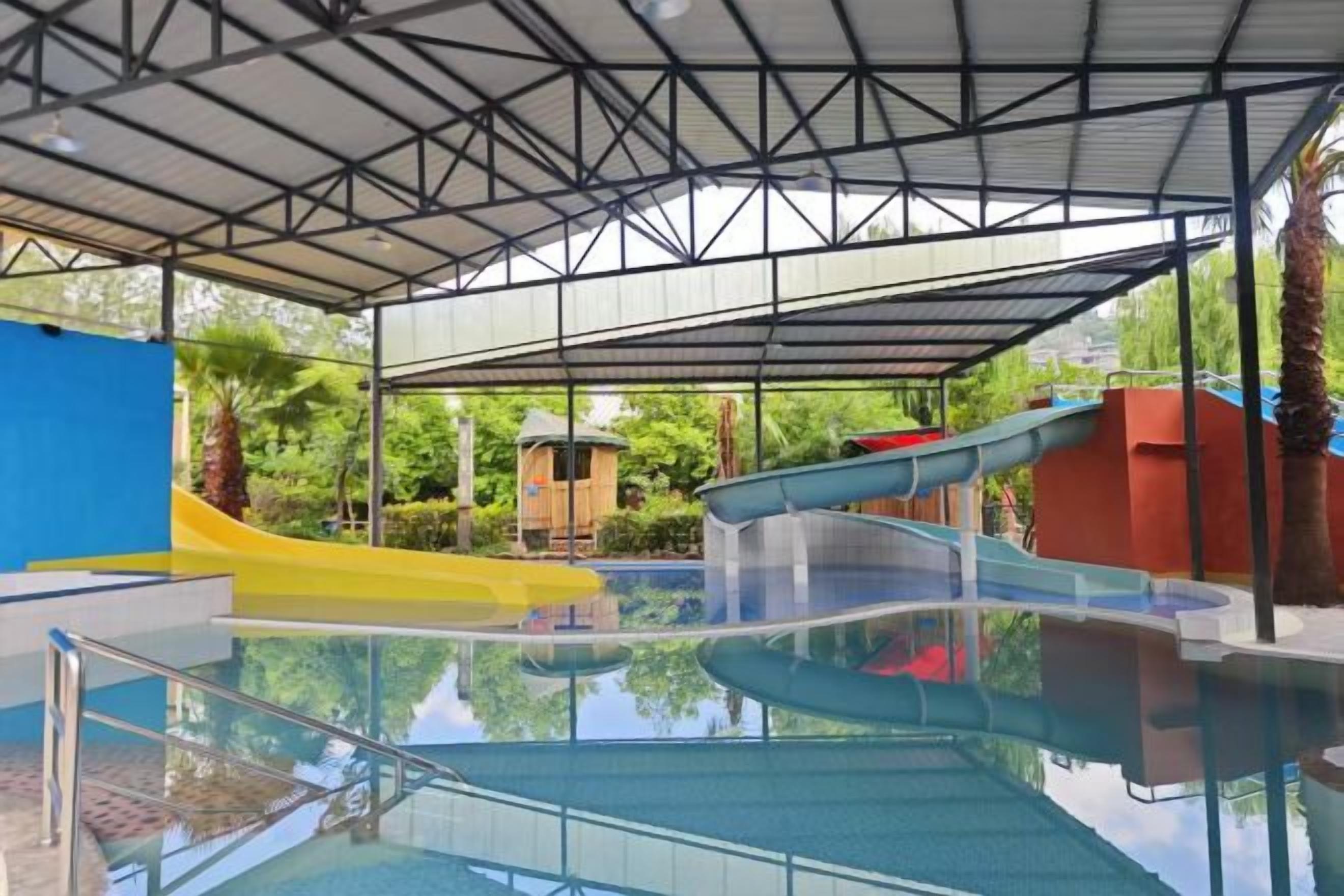 Una piscina interior con techo cubierto, toboganes y una pequeña zona de juegos.