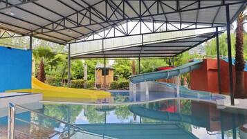 Una piscina interior con techo cubierto, toboganes y una pequeña zona de juegos.