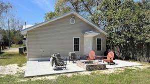 Einbungalow mit einer Terrassenanlage, die einen Feuerkorb, zwei Adirondack-Stühle und einen Grill beinhaltet.
