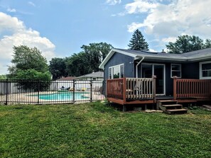 Ein Haus mit Schwimmbad, Terrasse und umzäunter Garten.