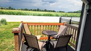 A balcony with a table and chairs, overlooking a field.