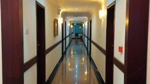 A hotel hallway with doors on both sides, a shiny floor, and wall-mounted lights. - Jinlang Mansion Hotel (Taishan)