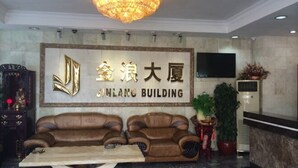 A reception area with a chandelier, a large sign reading "JINLANG BUILDING," and a sofa. - Jinlang Mansion Hotel (Taishan)
