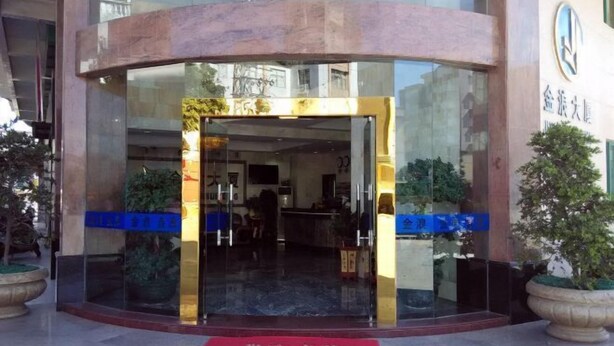 A hotel entrance with a glass door, a red carpet, and potted plants. - Jinlang Mansion Hotel (Taishan)