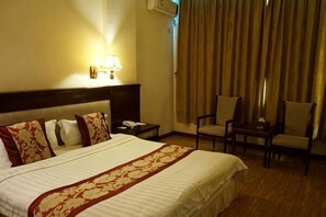 A hotel room with a large bed, two bedside tables, a desk with a chair, and a curtain. - Jinlang Mansion Hotel (Taishan)