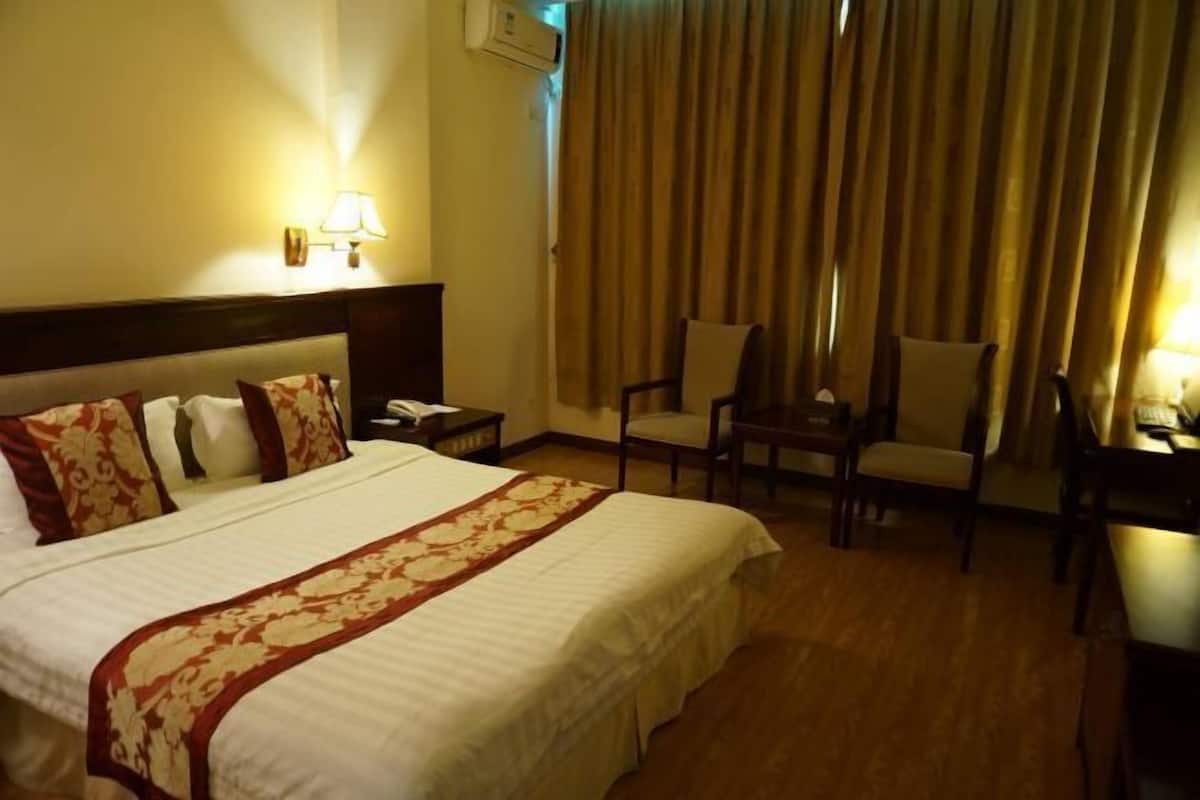Una habitación de hotel con una cama grande, una mesita de noche, un escritorio y una silla.