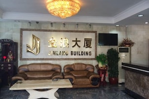 Un área de recepción con una araña, un sofá, una mesa y un letrero en la pared para Jinlang Building.