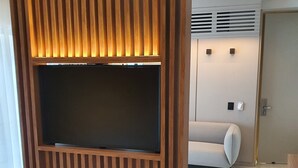 A modern living room with a built-in TV, a sofa, and a minimalist design. - Lastarria Hotel (Santiago)